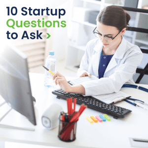 An image titled '10 Startup Questions to Ask' with a woman wearing a white lab coat at a desk pointing to a computer screen.