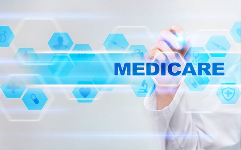 A person in a lab coat writes on a digital screen displaying the word "MEDICARE" with blue medical icons in the background.