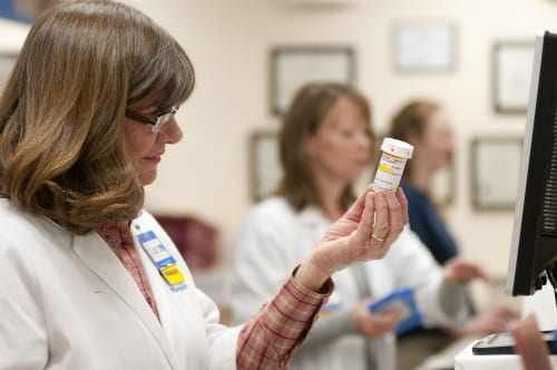 Walmart pharmacy associate examines a medication prescription bottle