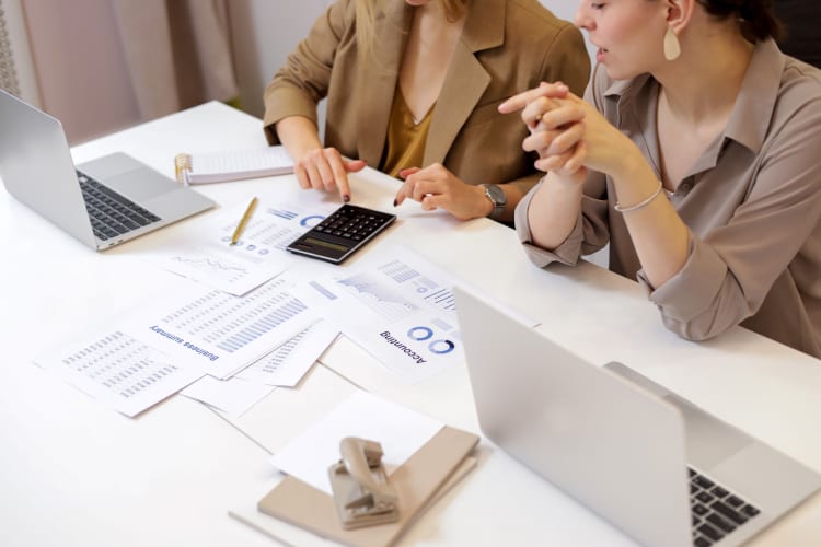 Consultants working on a calculator surrounded by paperwork