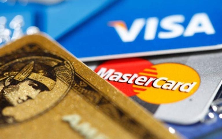 Close-up of several credit cards, including American Express, Mastercard, and Visa, stacked together, showing their logos prominently.