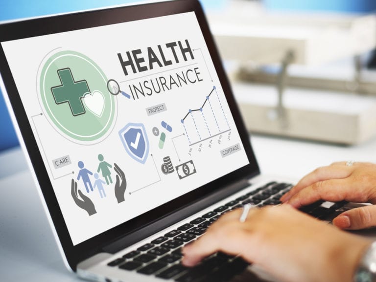 Person using a laptop displaying a health insurance concept with icons, graphs, and text related to care, protection, and coverage.