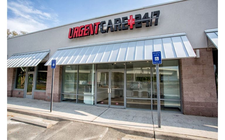 The exterior of an urgent care clinic with a sign reading "Urgent Care 24/7" above the entrance and two accessible parking spaces in front.