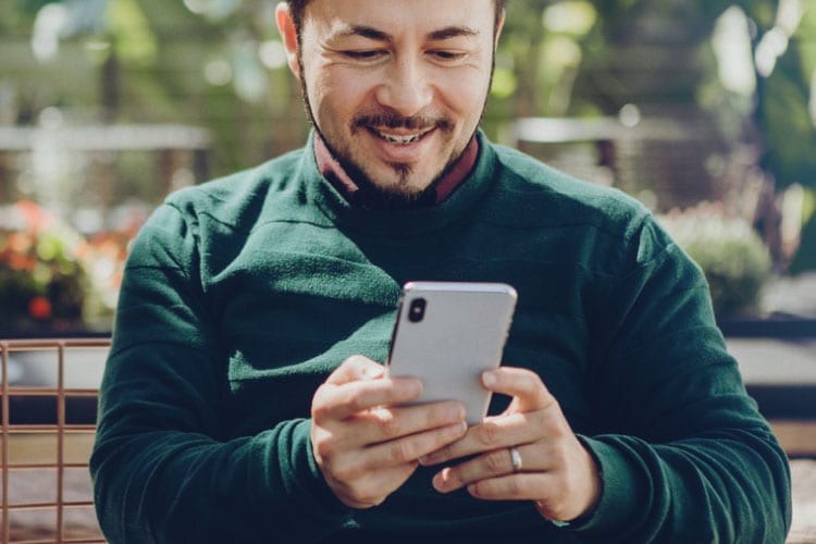 Man smiling, holding mobile phone