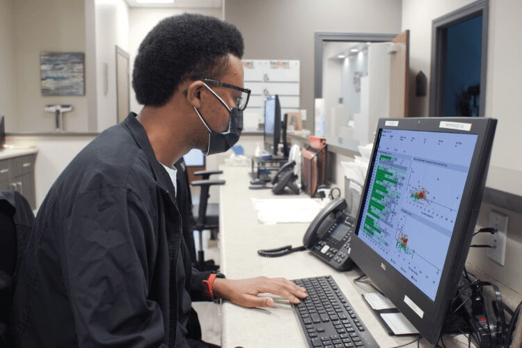 Masked doctor reviewing throughput metrics on a computer screen.