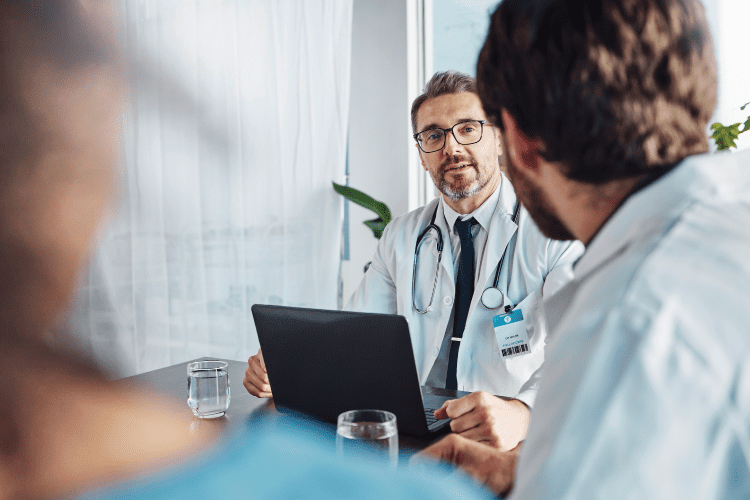 doctor in front of a computer conversing with other people