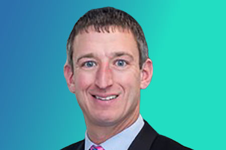 A man in a suit and tie smiles at the camera against a blue to teal gradient background, embodying confidence—much like the reassurance found at urgent care during pivotal moments, reflecting the peak end rule of memorable experiences.