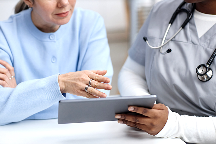 A patient and a healthcare professional discuss information displayed on a tablet during a medical consultation.
